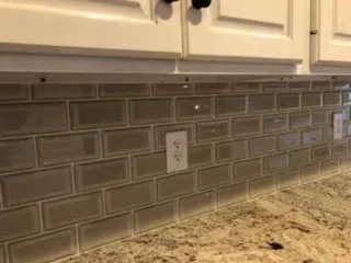 A kitchen with a subway tile backsplash and granite counter tops.