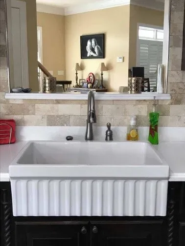 A kitchen sink with a faucet and a mirror above it.