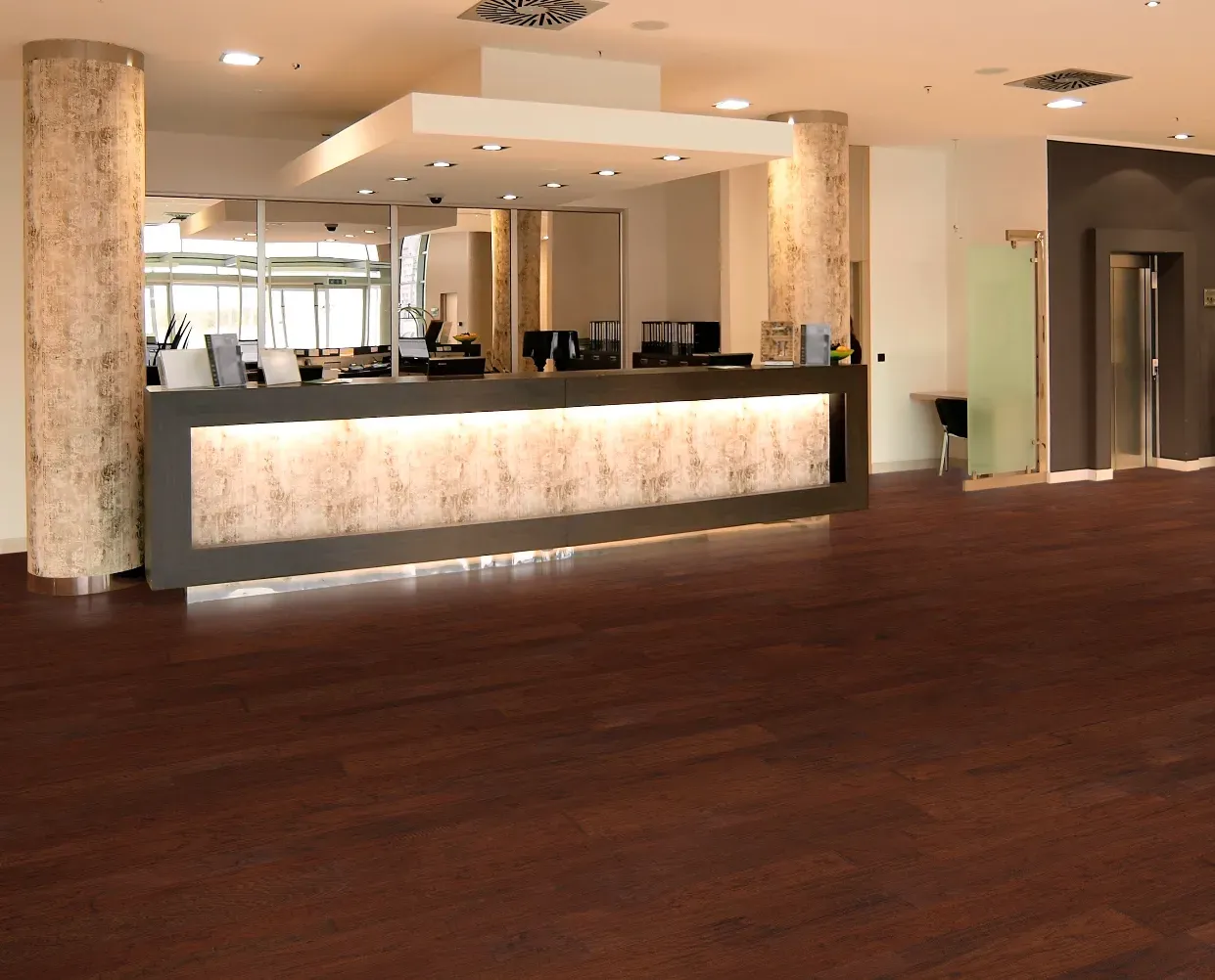 A hotel lobby with a wooden floor and a counter