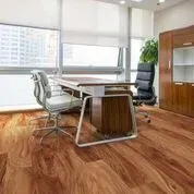 A room with a wooden floor , a desk and chairs.