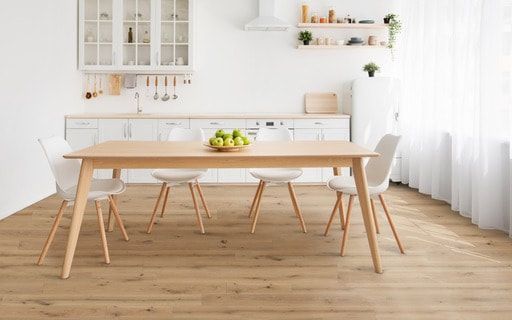 A kitchen with a wooden table and chairs and a bowl of apples on it.