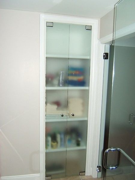 A bathroom with a glass door and shelves