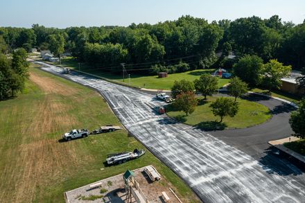 an aerial view of a road being paved in a residential area