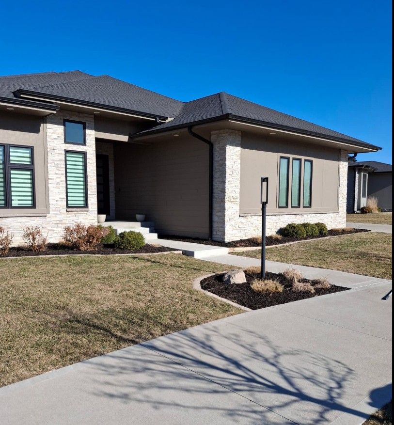 Modern suburban house exterior with a concrete driveway, trimmed lawn, and blue sky