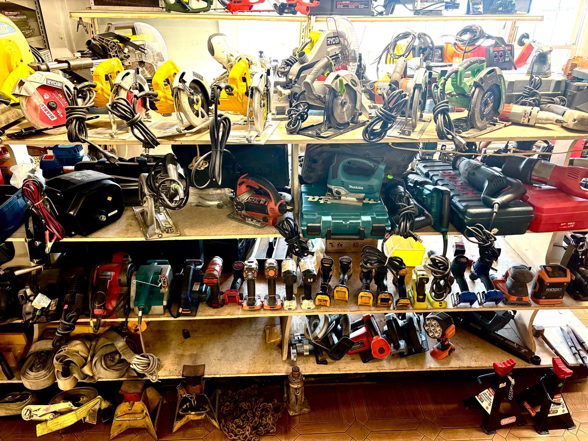 Shelves filled with various power tools, including saws and drills, in a workshop setting.