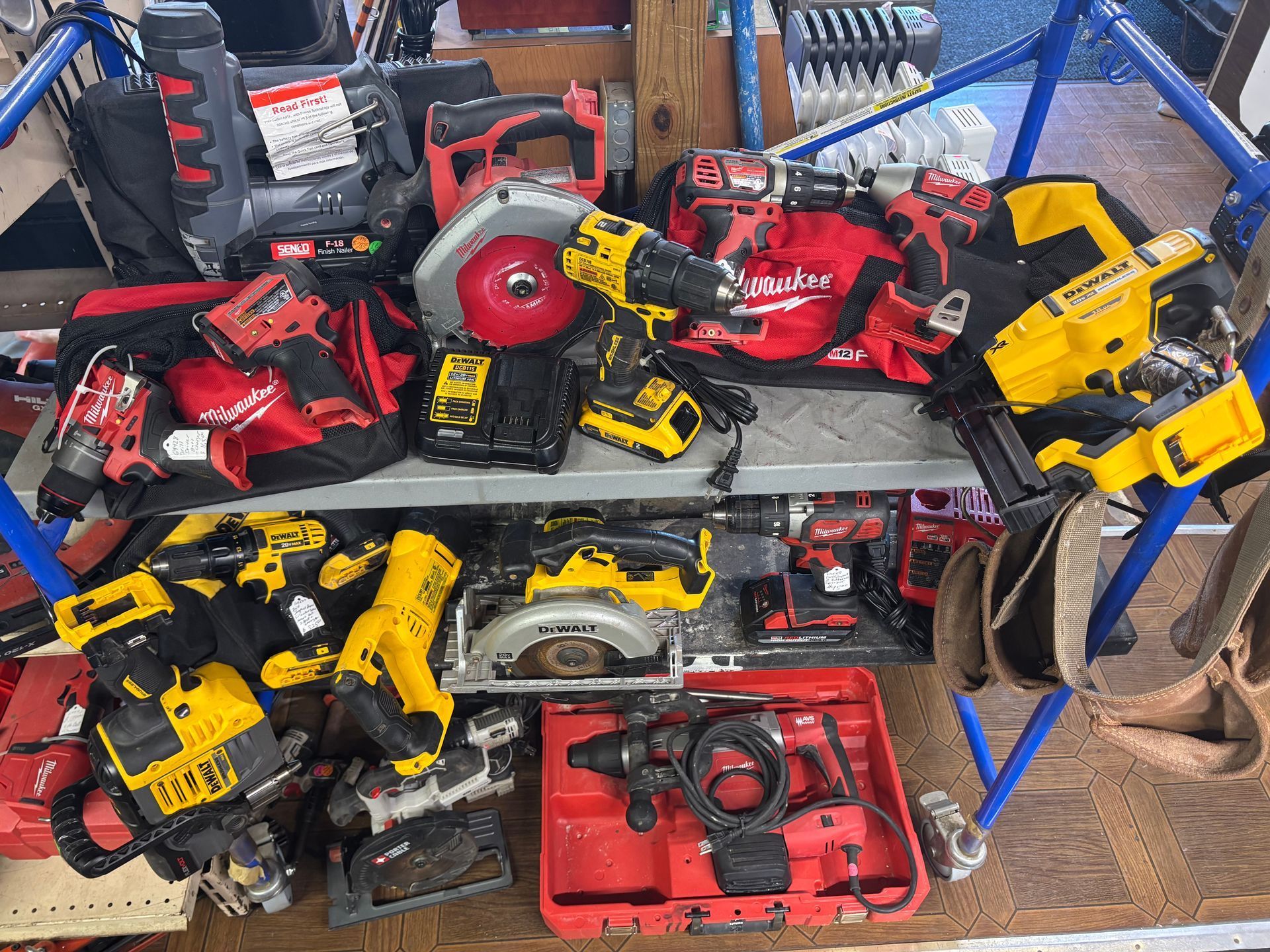 Assortment of power tools, including saws and drills, displayed on a shelf. Mostly yellow and red tools.