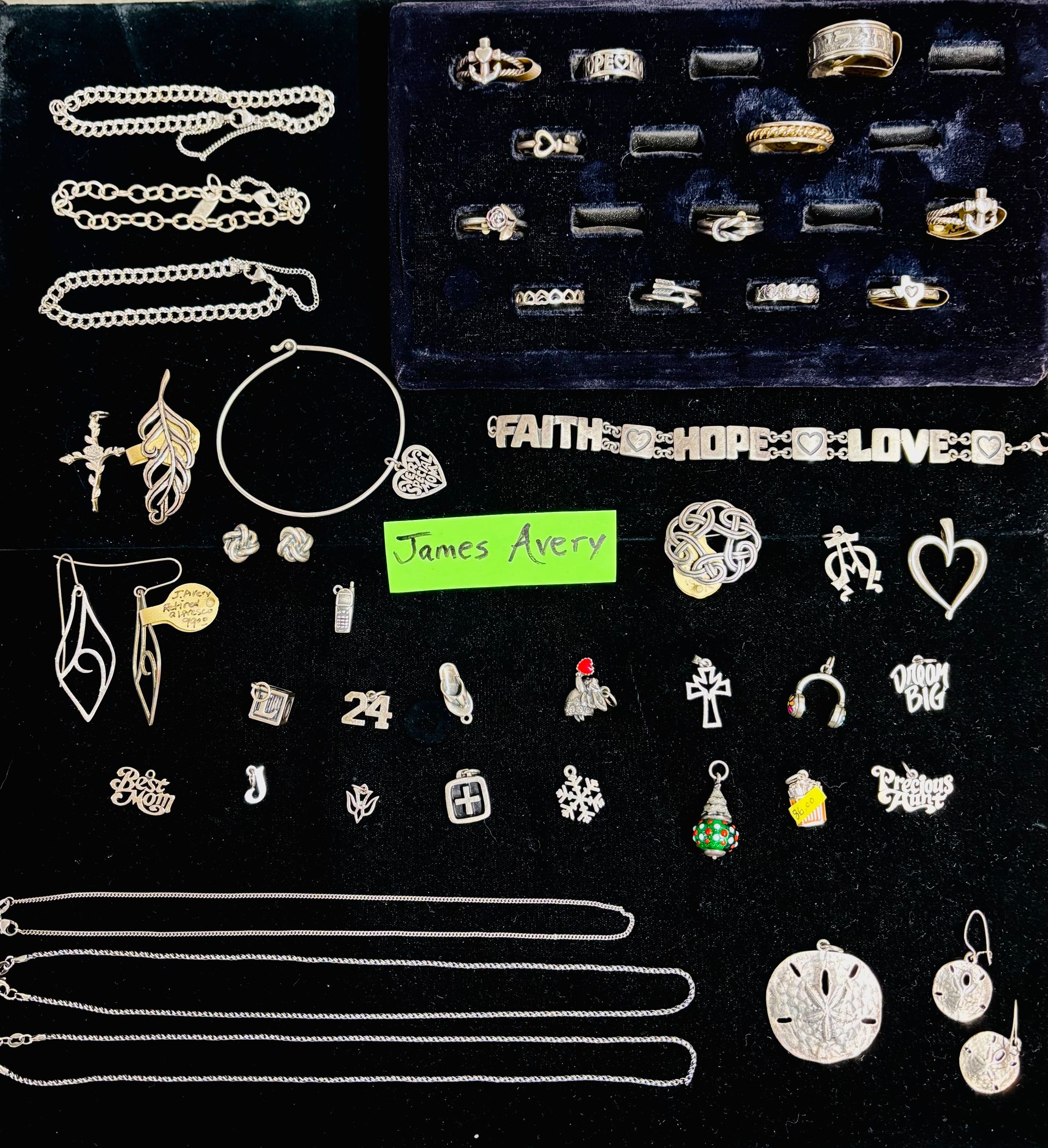Jewelry display with bracelets, rings, necklaces, and charms against a black background.