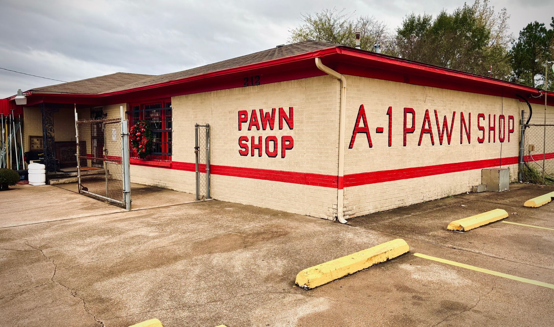 A-1 Pawn Shop building with red trim and lettering, open gate, and parking blocks.