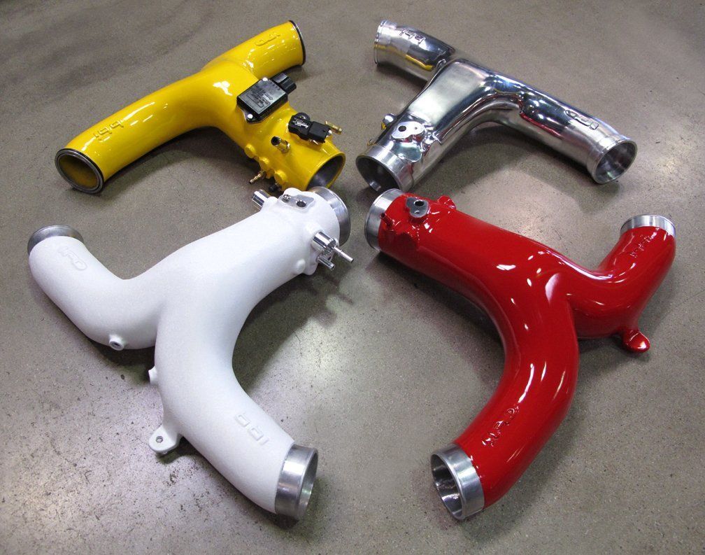 Three different colored pipes are sitting on a concrete surface