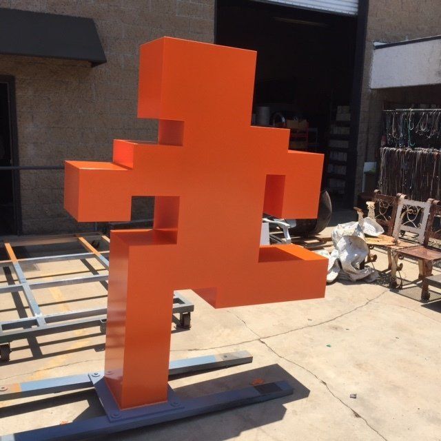 A large orange sculpture is sitting outside of a building