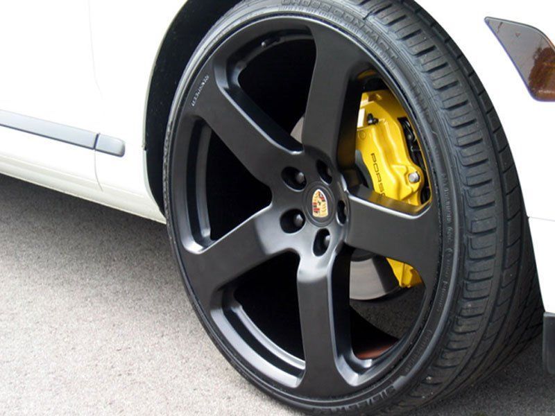 A white car with black wheels and yellow brake calipers