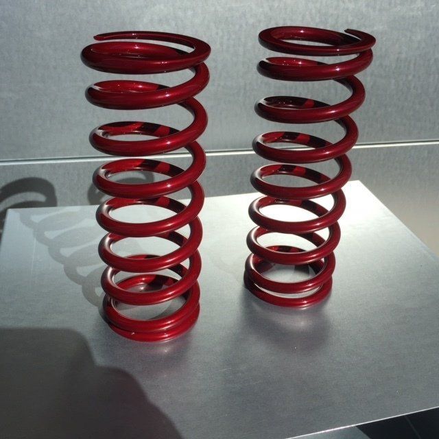 Two red coil springs are sitting on a metal surface