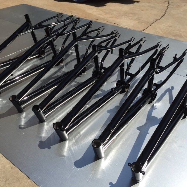 A bunch of bicycle frames are lined up on a metal surface