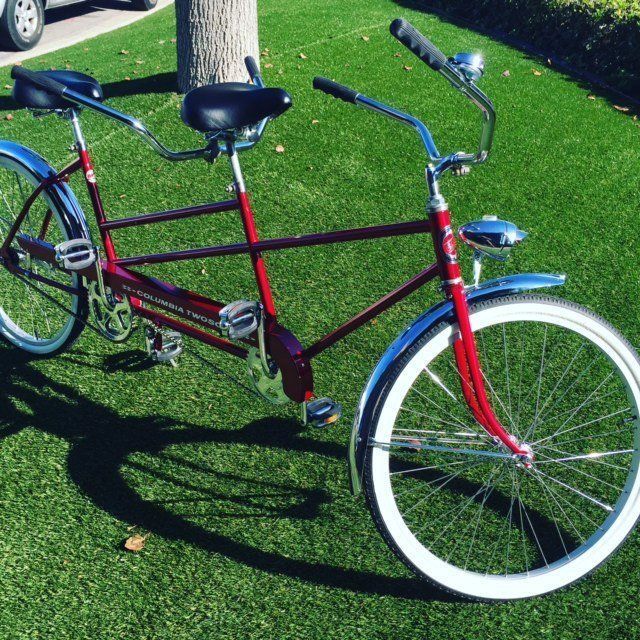 A red tandem bike is parked on the grass