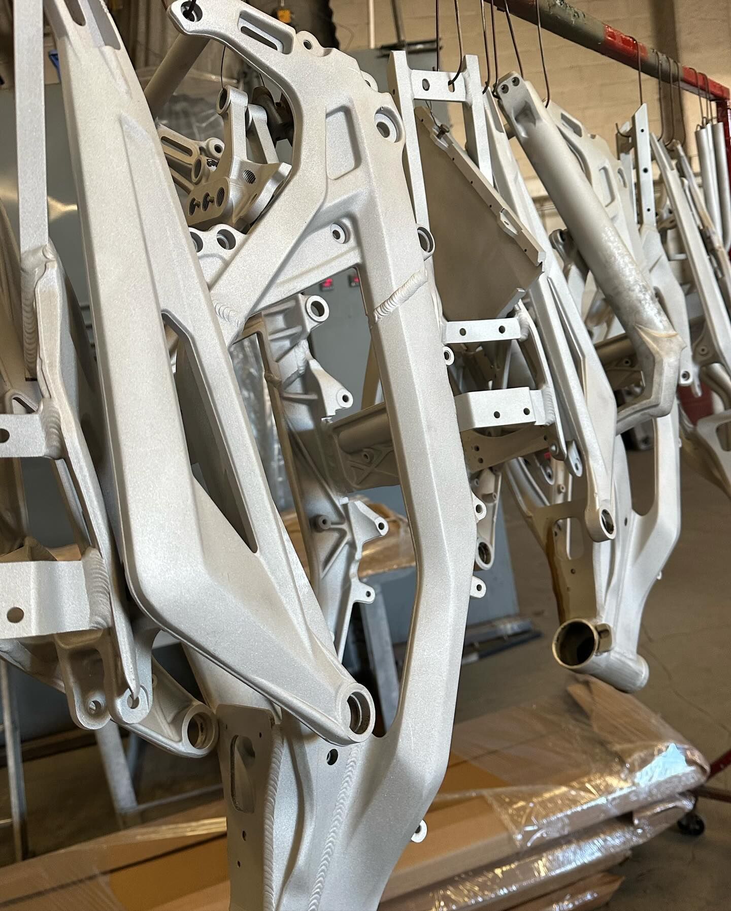 A bunch of white motorcycle frames hanging on a rack