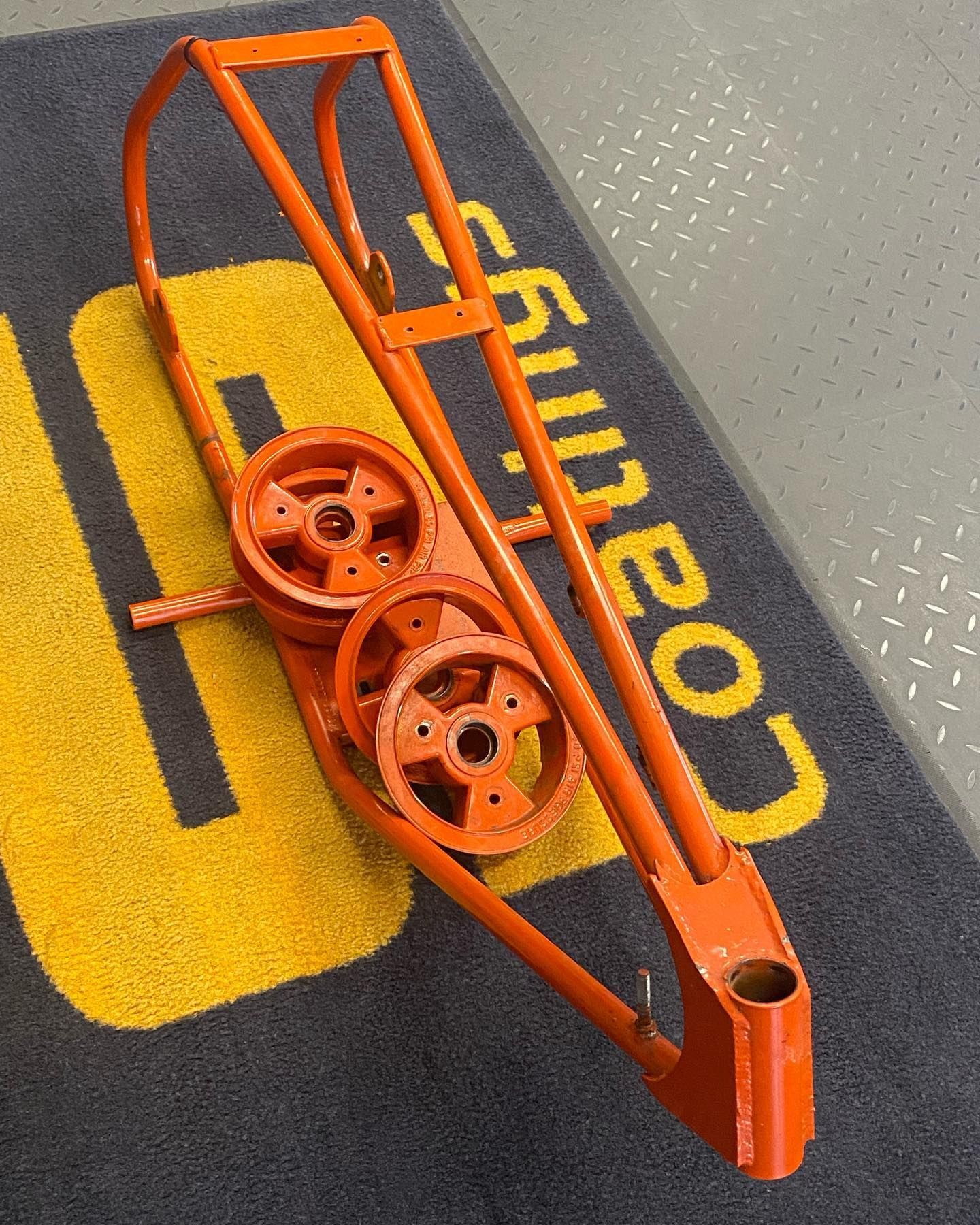 A piece of orange metal is sitting on a mat that says coatings