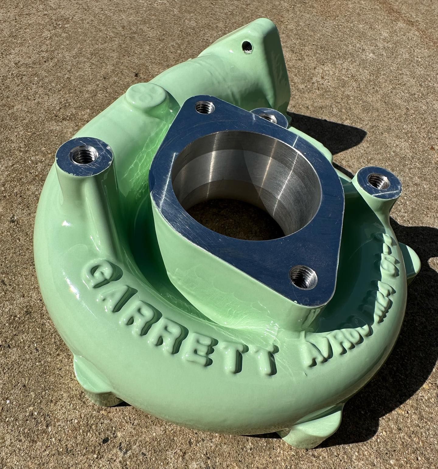 A green garrett turbocharger is sitting on the ground