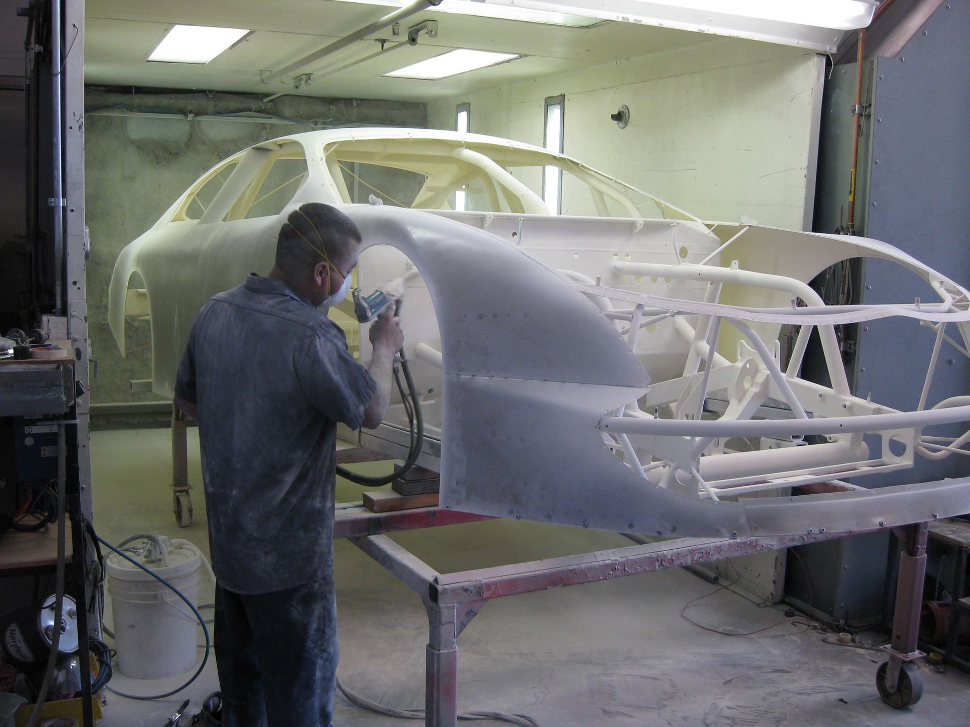 A man is spray painting a car in a garage