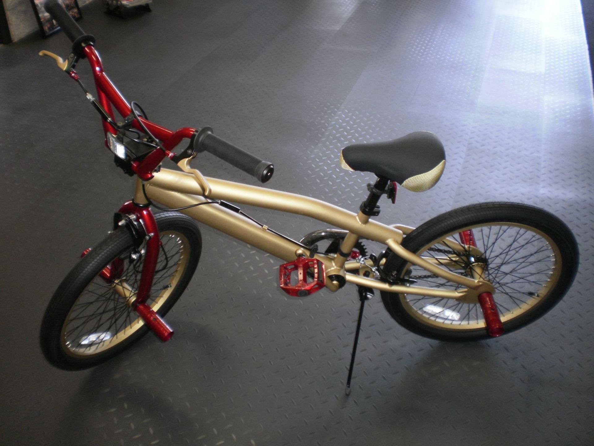 A gold and red bmx bike is parked on the floor
