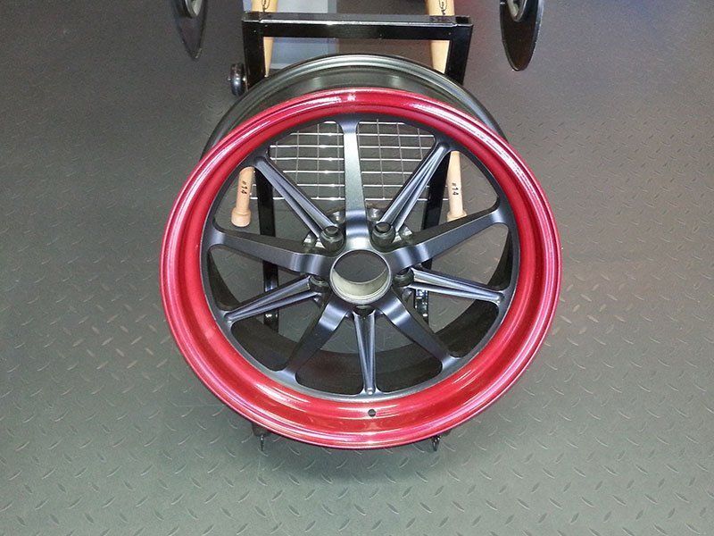 A black wheel with a red rim is on display