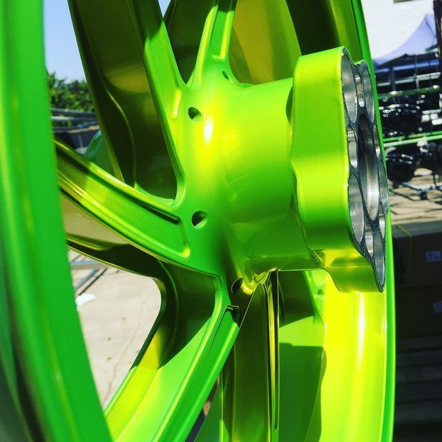 A close up of a green and yellow motorcycle wheel