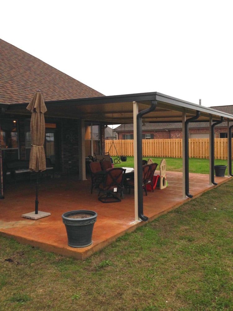 A patio with a table and chairs under a canopy in front of a house.