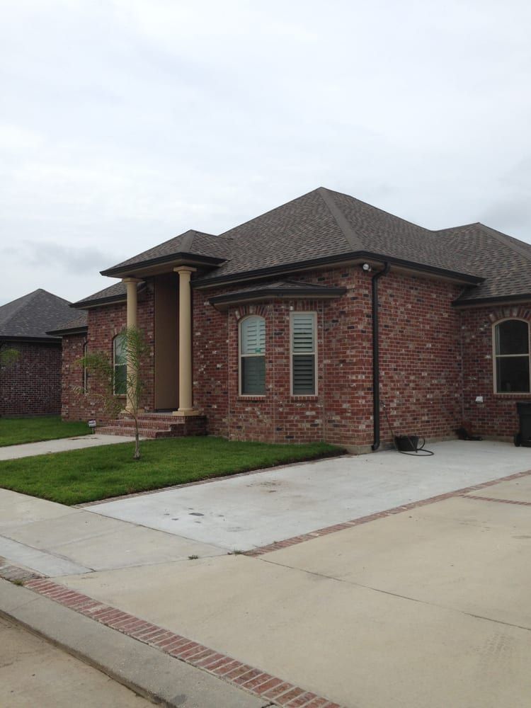 A brick house with a gray roof and a driveway