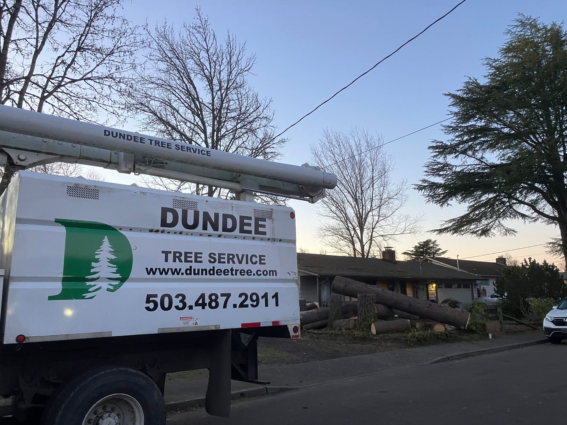 A dundee tree service truck is parked on the side of the road
