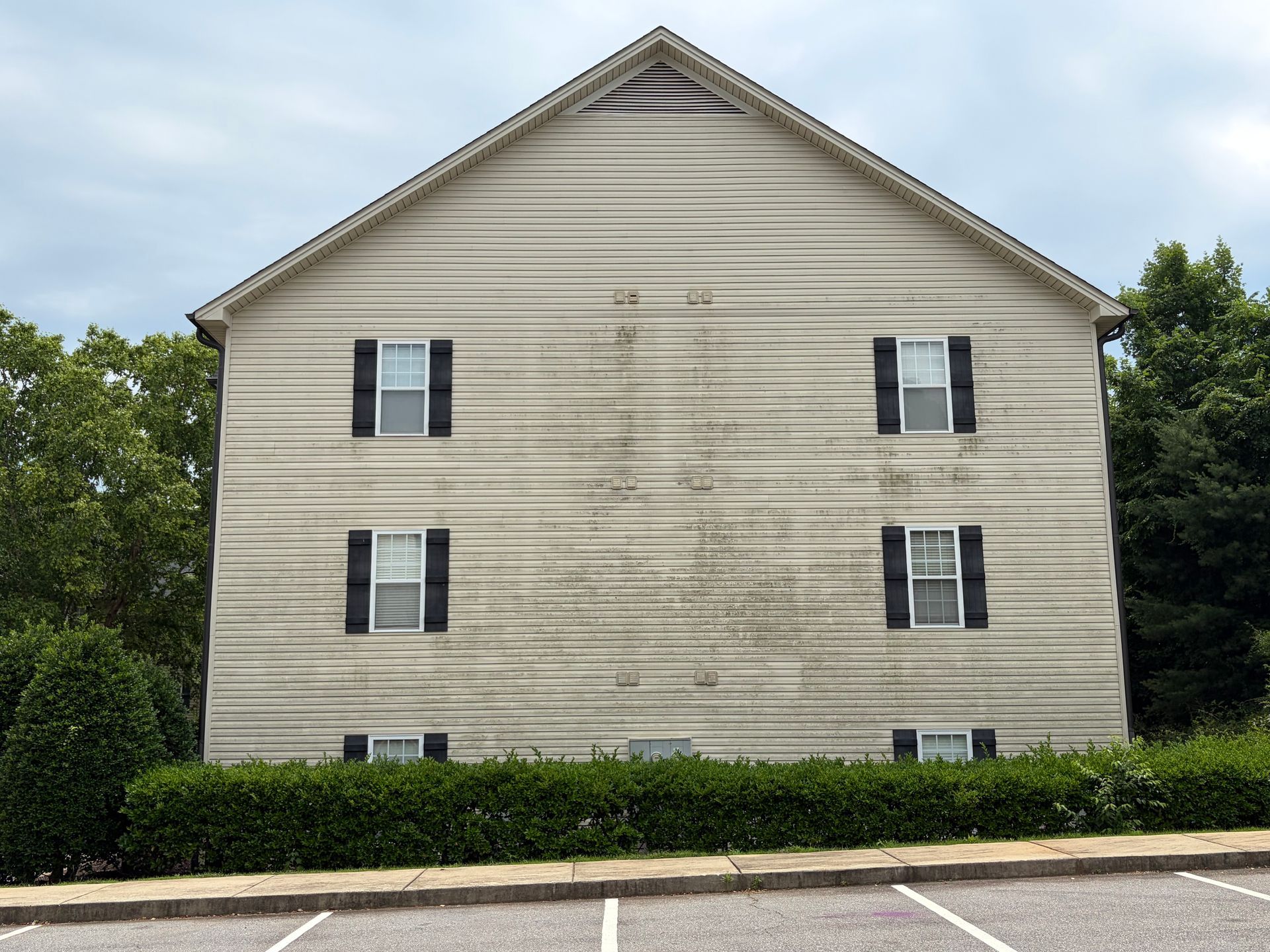 White house exterior with black shutters and a neatly trimmed hedge in front