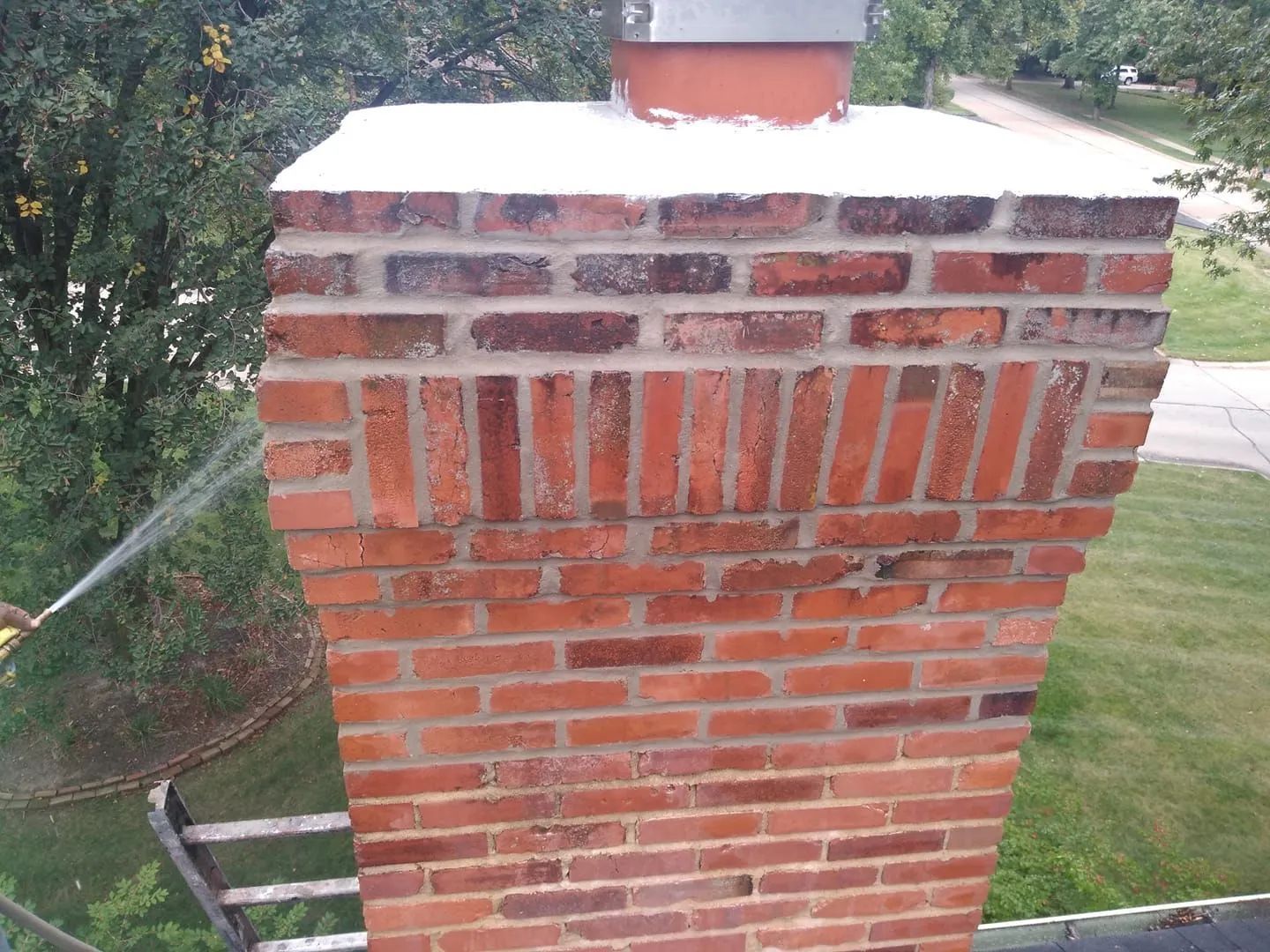 Brick chimney on a rooftop with water spraying from the left side