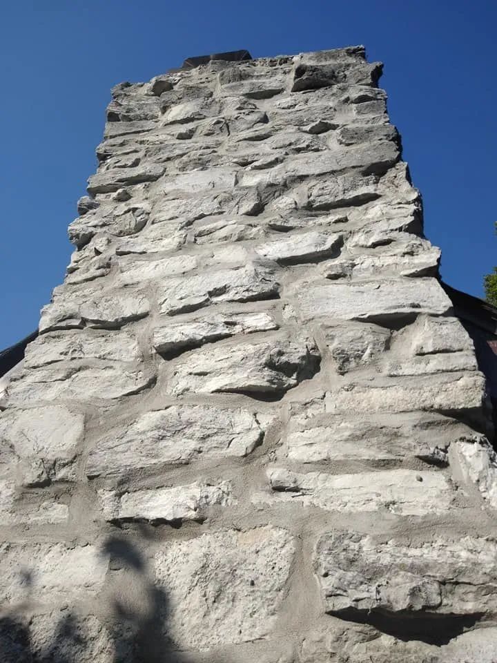 Close-up of a weathered stone chimney or wall against a clear blue sky
