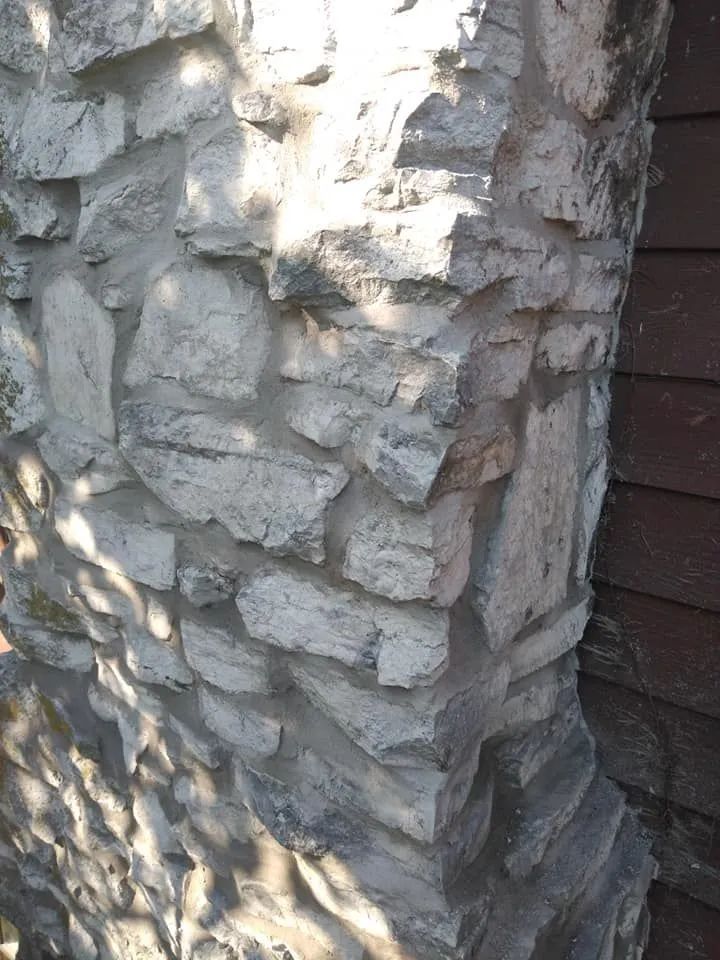 Close-up of a rough gray stone wall corner in sunlight and shadow