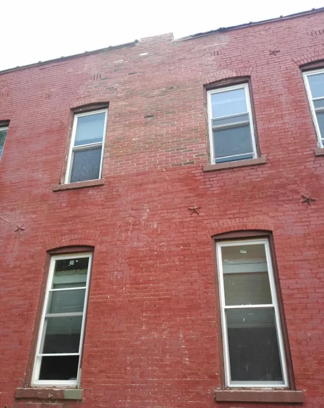 Red brick building facade with four narrow windows under a clear sky.