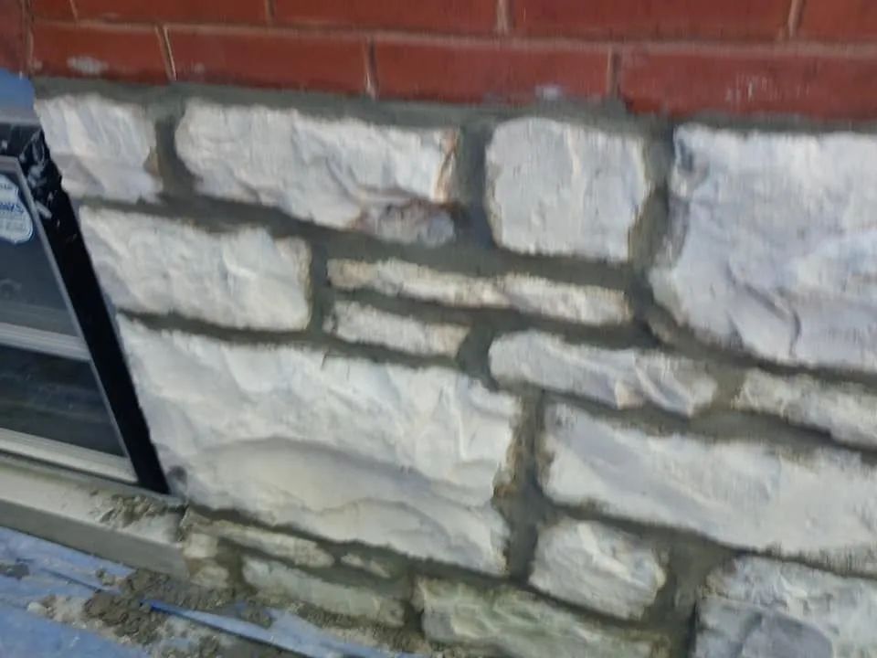 Close-up of a stone wall with a red brick top and dark mortar lines