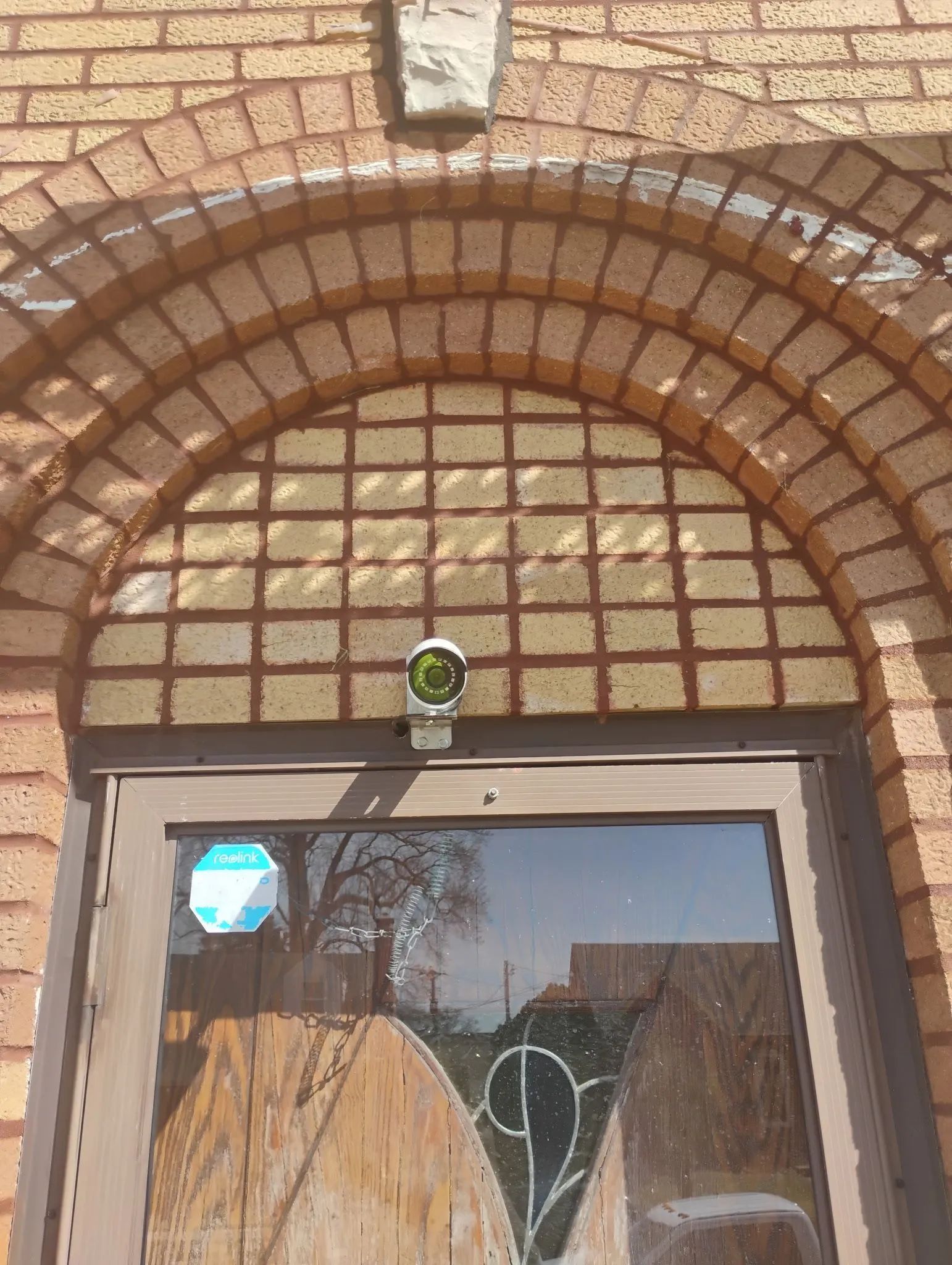 Brick arched doorway with a glass door and small security camera above it