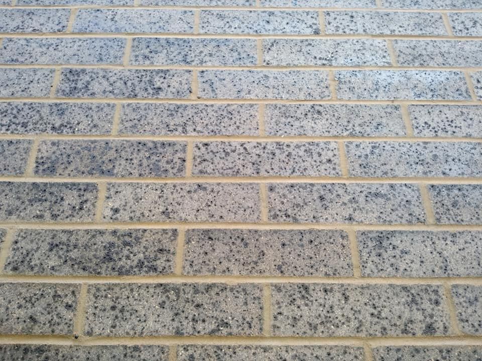 Close-up of a tan brick wall with speckled gray mortar lines