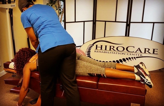 Massage therapy session in a clinic, with a client on a table and a therapist leaning over her