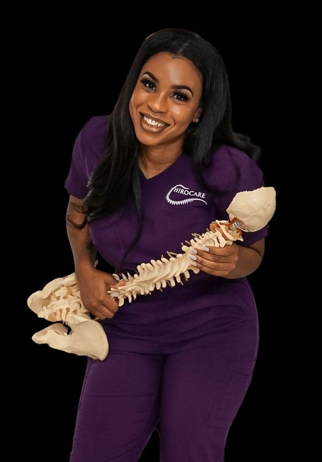 Woman in purple scrubs smiling and holding a plastic spine model against a black background