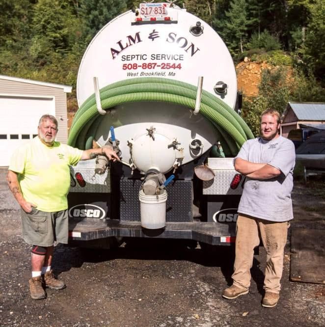 Two men standing in front of an alm & son septic service truck