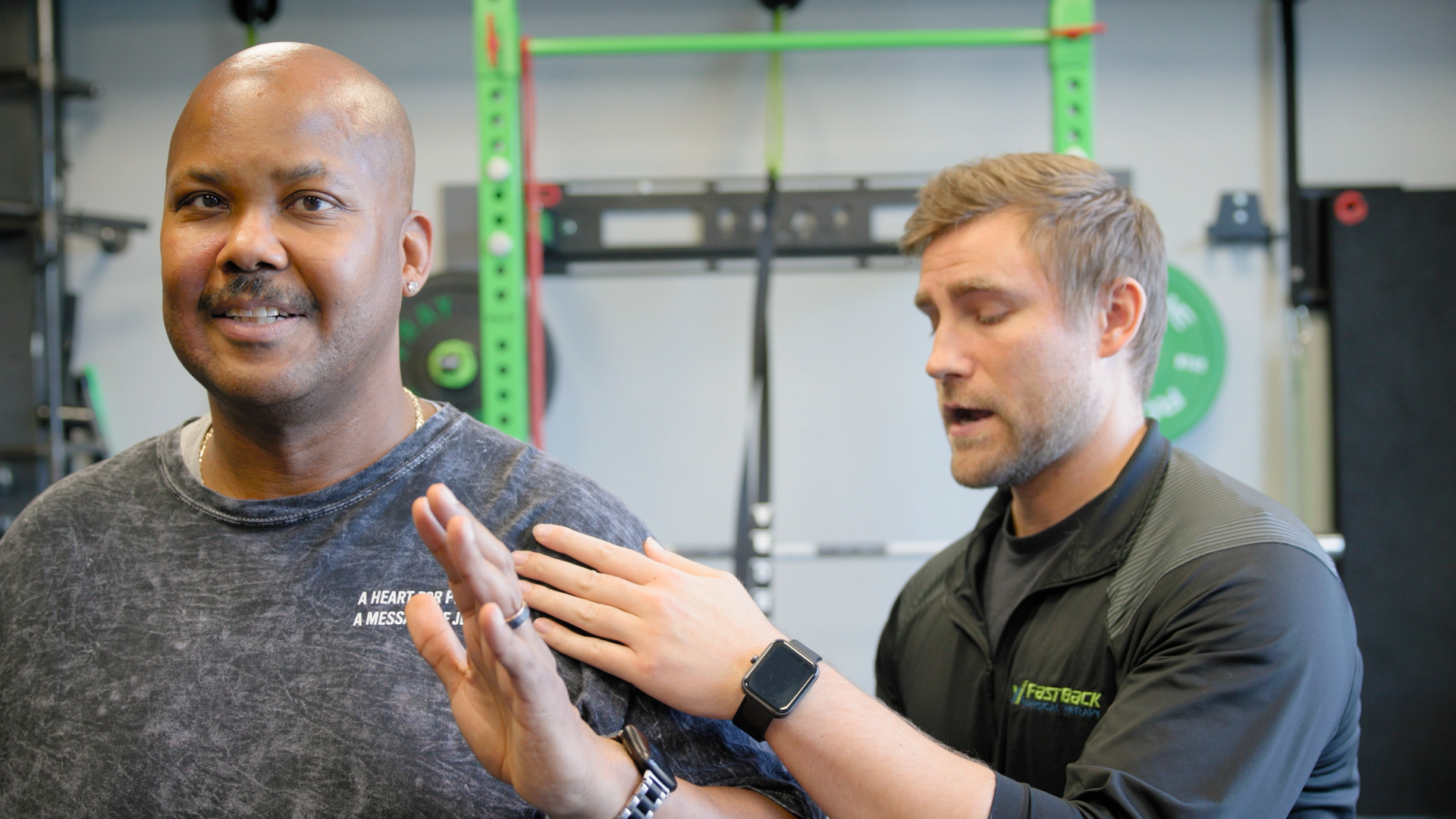 A man is talking to another man in a gym.