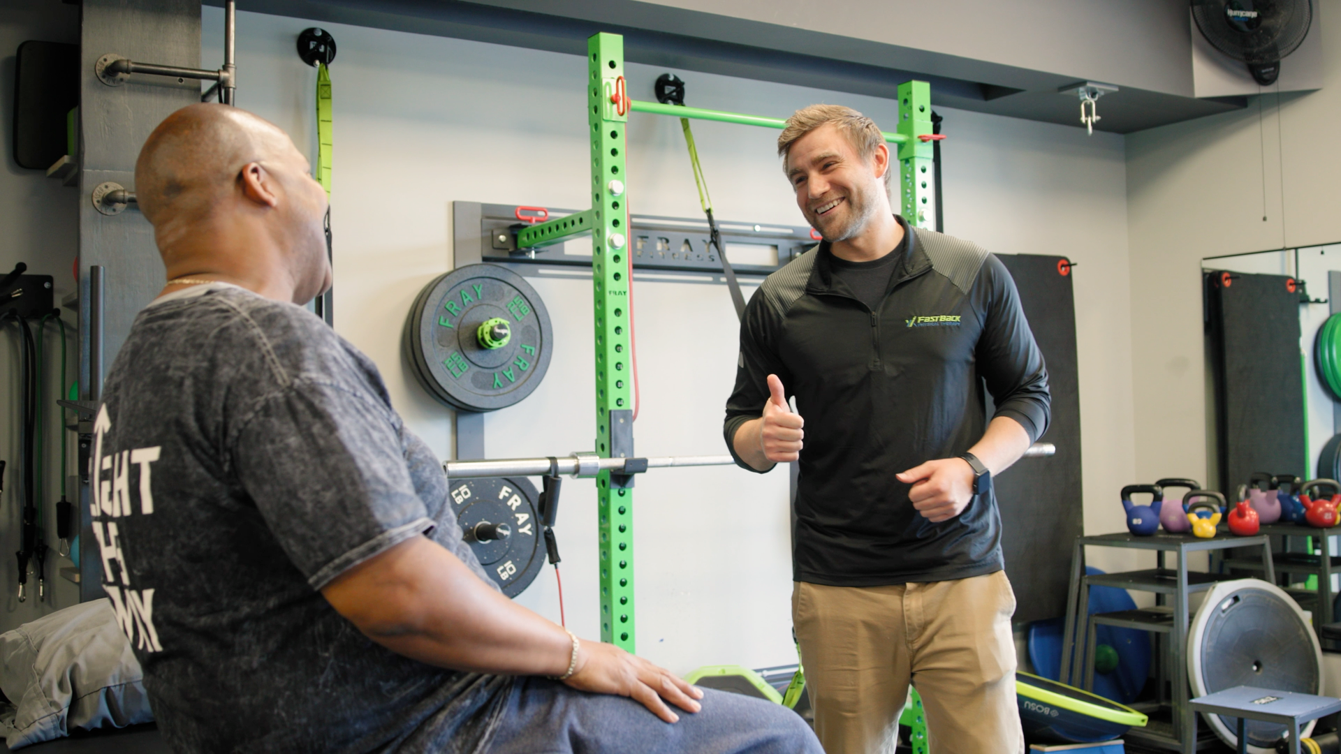 A man in a wheelchair is talking to a man in a gym.