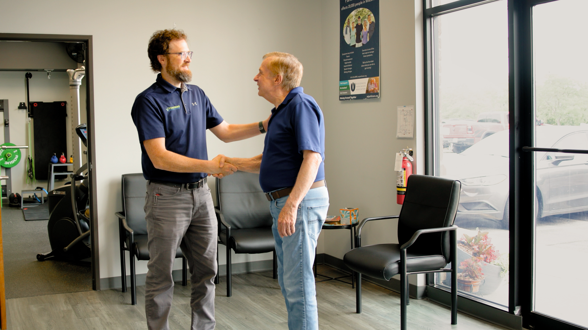 A man is shaking hands with another man in a waiting room.