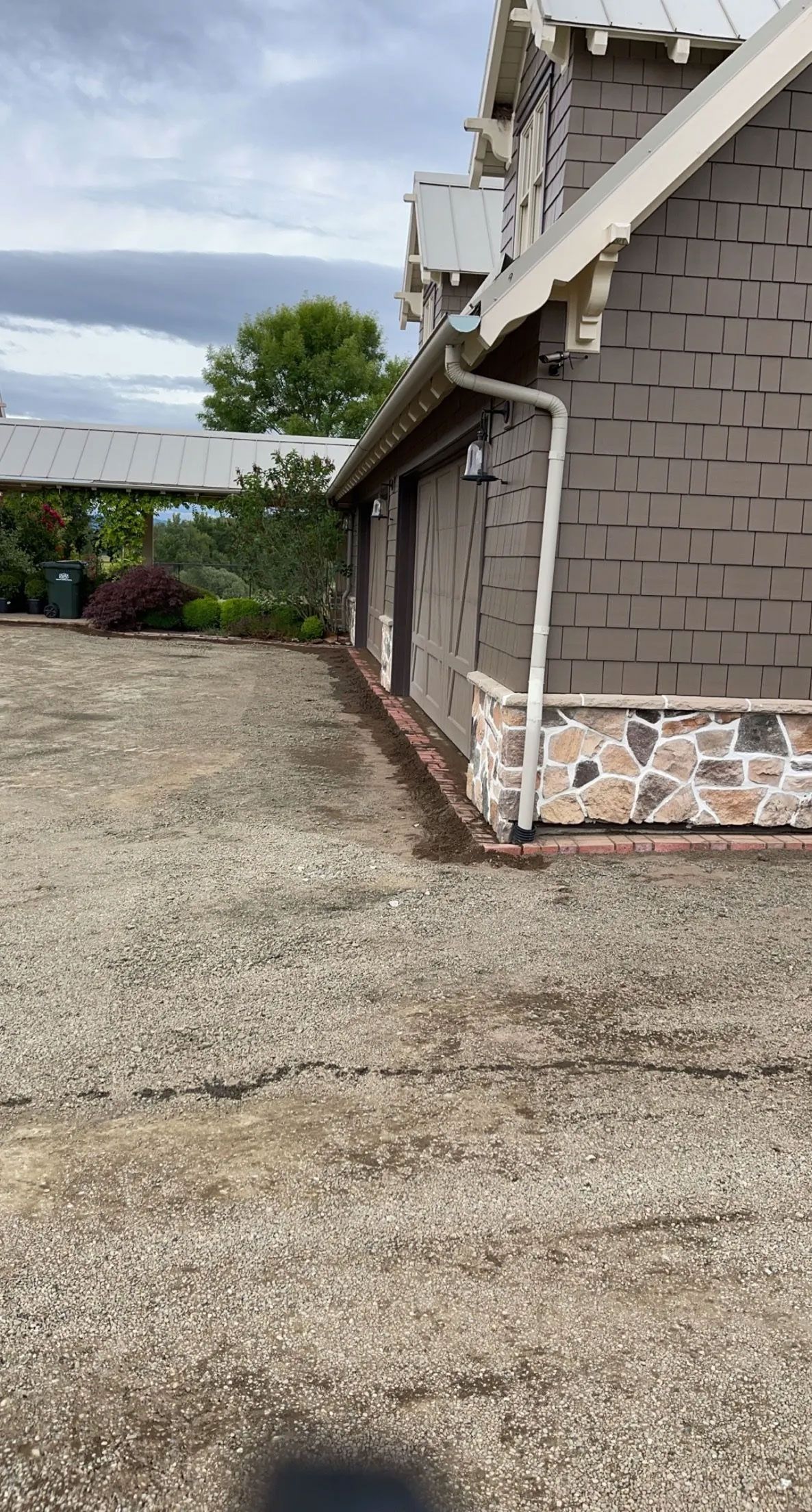 A brick house with a gravel driveway in front of it.