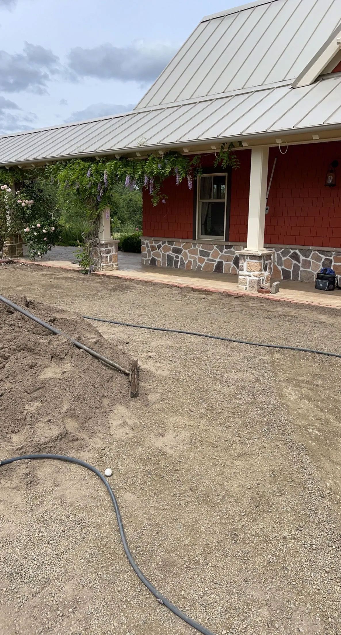 A red brick house with a metal roof and a hose in front of it.