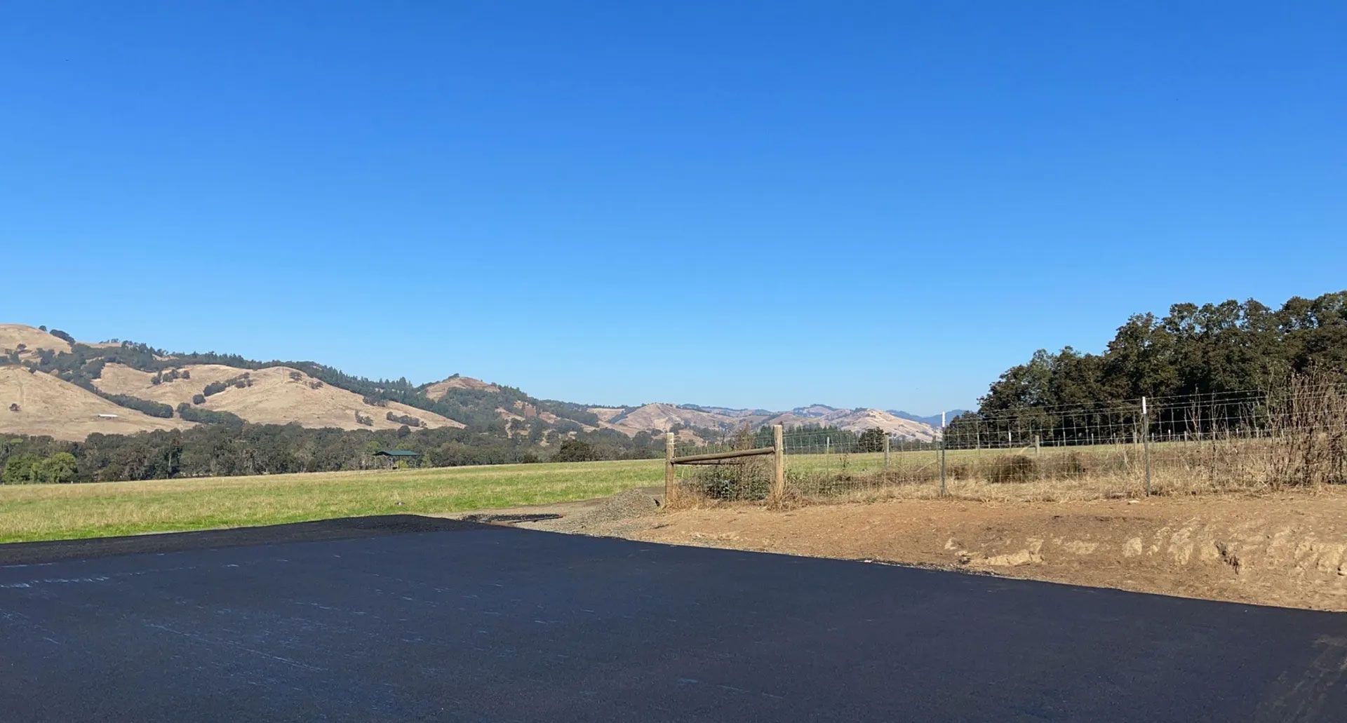 A road going through a field with mountains in the background.