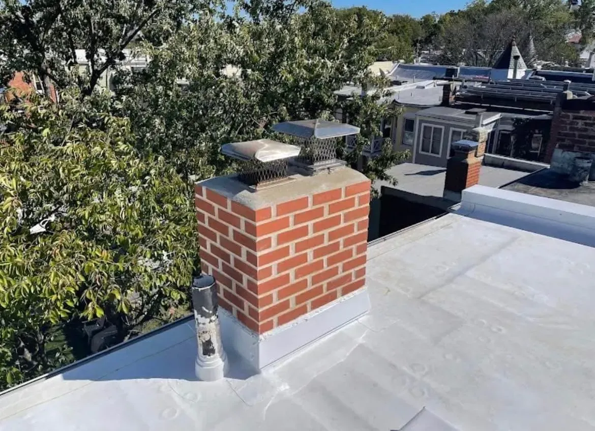 A brick chimney is on the roof of a building.
