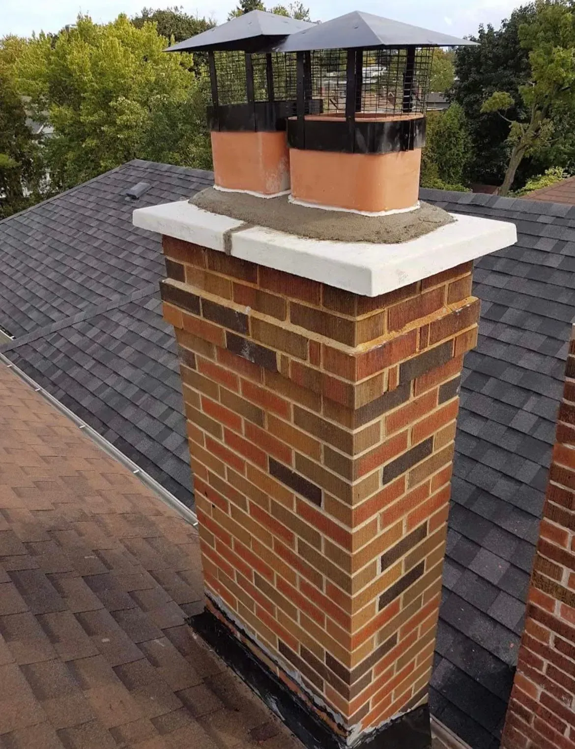 A brick chimney is sitting on top of a roof.