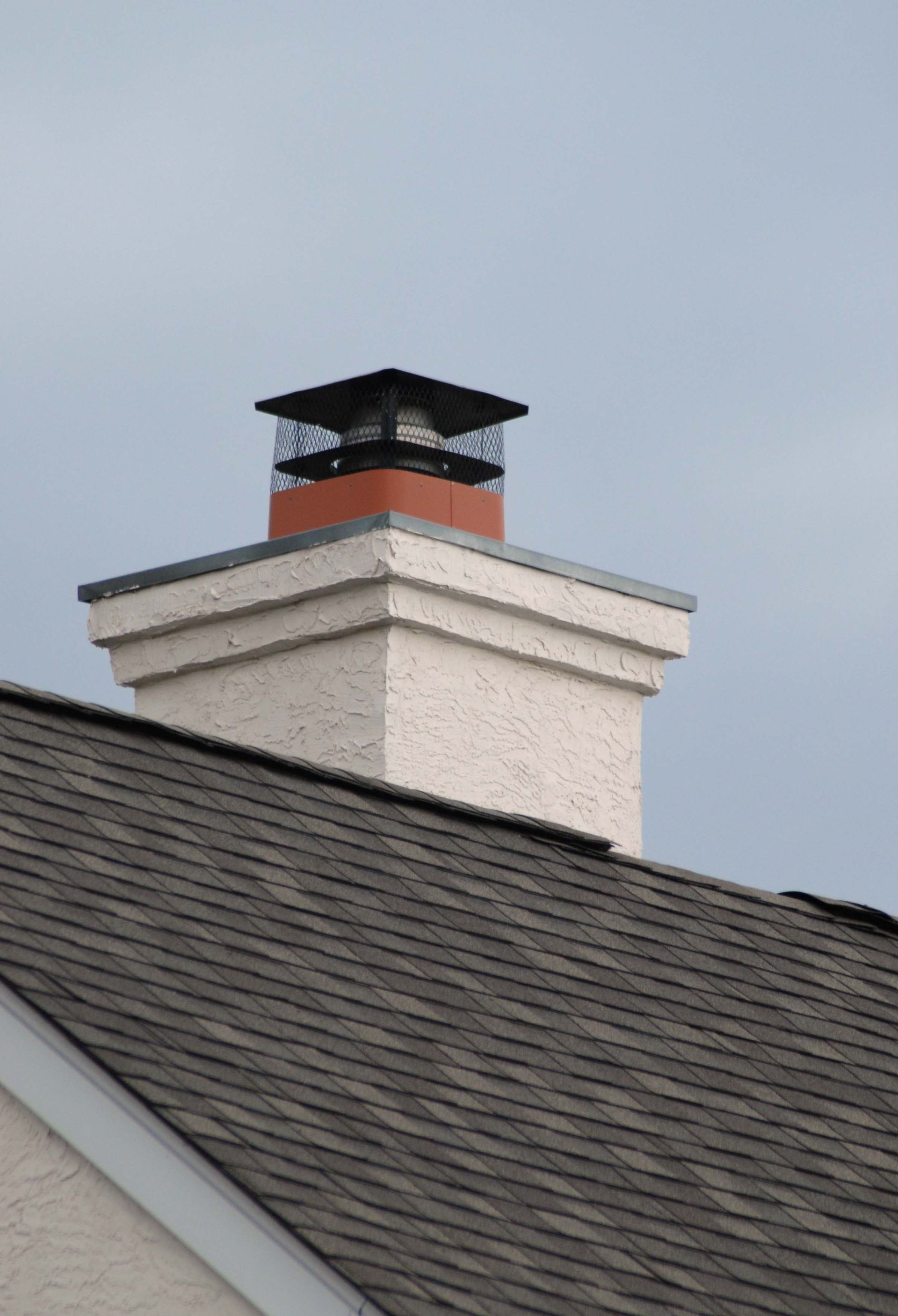 A chimney on top of a roof with a blue sky in the background
