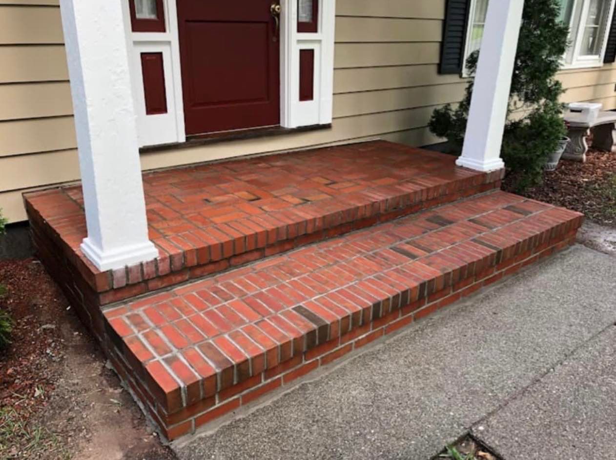 A brick porch with steps leading up to the front door of a house