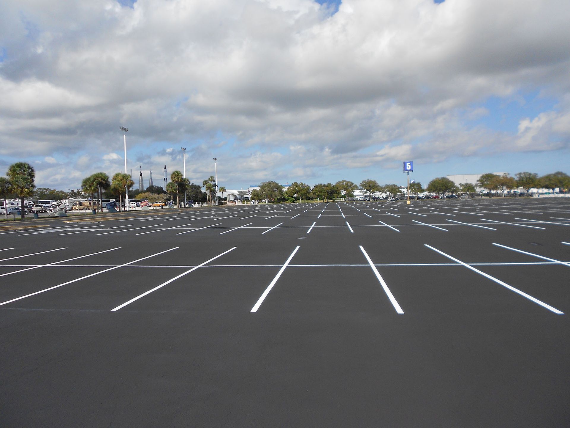 Empty parking lot with white painted lines under a cloudy sky